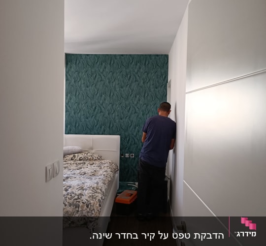 אדם עובד ליד קיר עם טפט ירוק